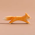 Ein grosser Fuchs ist in laufender Position, hat orangenes Fell, einen Schwanz mit weißer Spitze und weißes Bauchfell. Es schaut nach rechts.