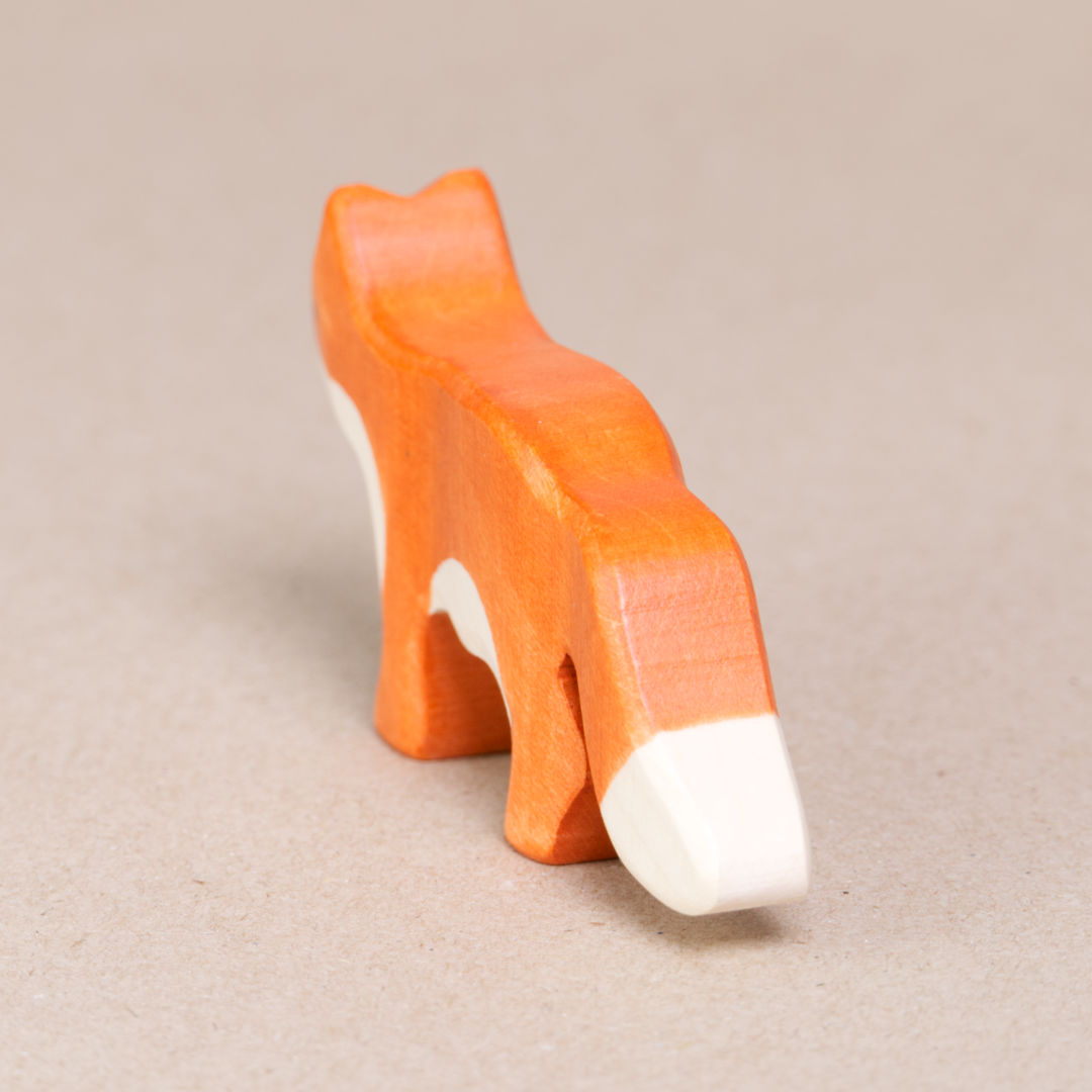 Hinteransicht eines orangenen Fuchses mit weißer Schwanzspitze von Holztiger.