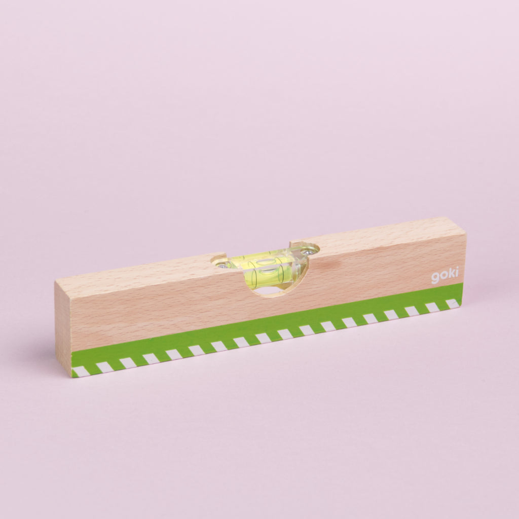 Wasserwaage von der Marke goki aus Holz mit einer Einkerbung an der oberen Seite in der sich ein kleines Behältnis befindet, in dem Flüssigkeit und eine Luftblase sind. Das Flüssigkeitsbehältnis ist mit Schrauben fixiert und an der unteren Seite der Wasserwaage ist ein grünfarbiger Aufdruck mit weißen Linien darin zu sehen.