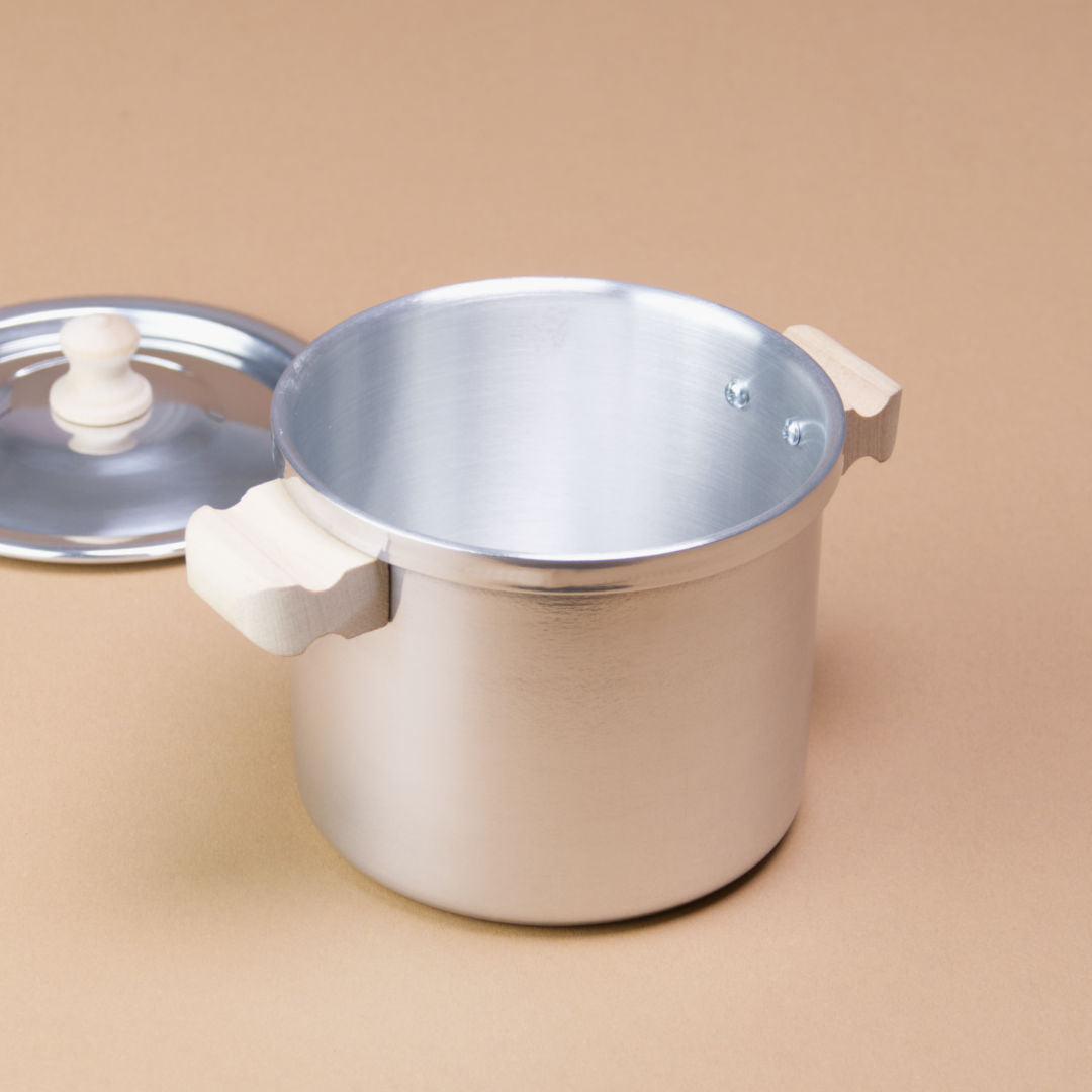 Ein Henkeltopf aus Aluminium hat Holzgriffe und einen Durchmesser von 10 cm. Der Deckel liegt daneben.