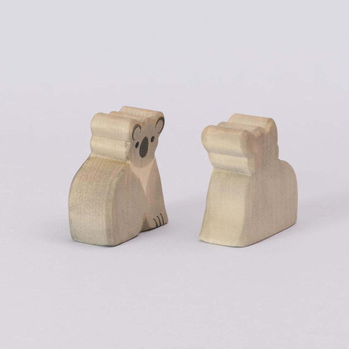 Zwei Koalas von Ostheimer, aus Holz zum Spielen, in den Farben grau und schwarz für das Gesicht. Die Koala werden seitlich zueinander gedreht gezeigt.