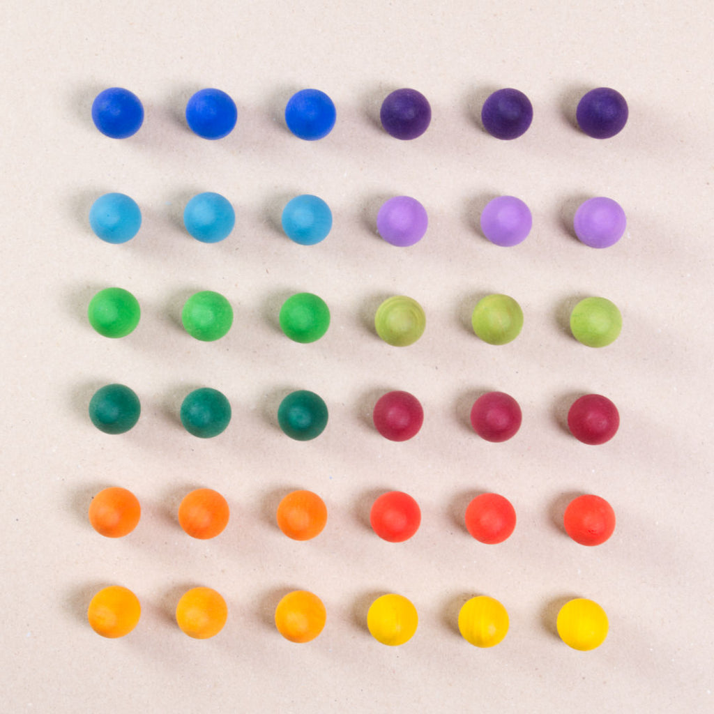 36 Regenbogen Eier aus Holz von Grapat in 12 unterschiedlichen Farben. Dunkelblau, dunkellila, hellblau, pastelllila, grasgrün, hellgrün, dunkelgrün, dunkelrot, orange, rot, sonnengelb und senfgelb. Gemeinsam als Quadratischer Block aufgebaut. Ansicht von Oben.