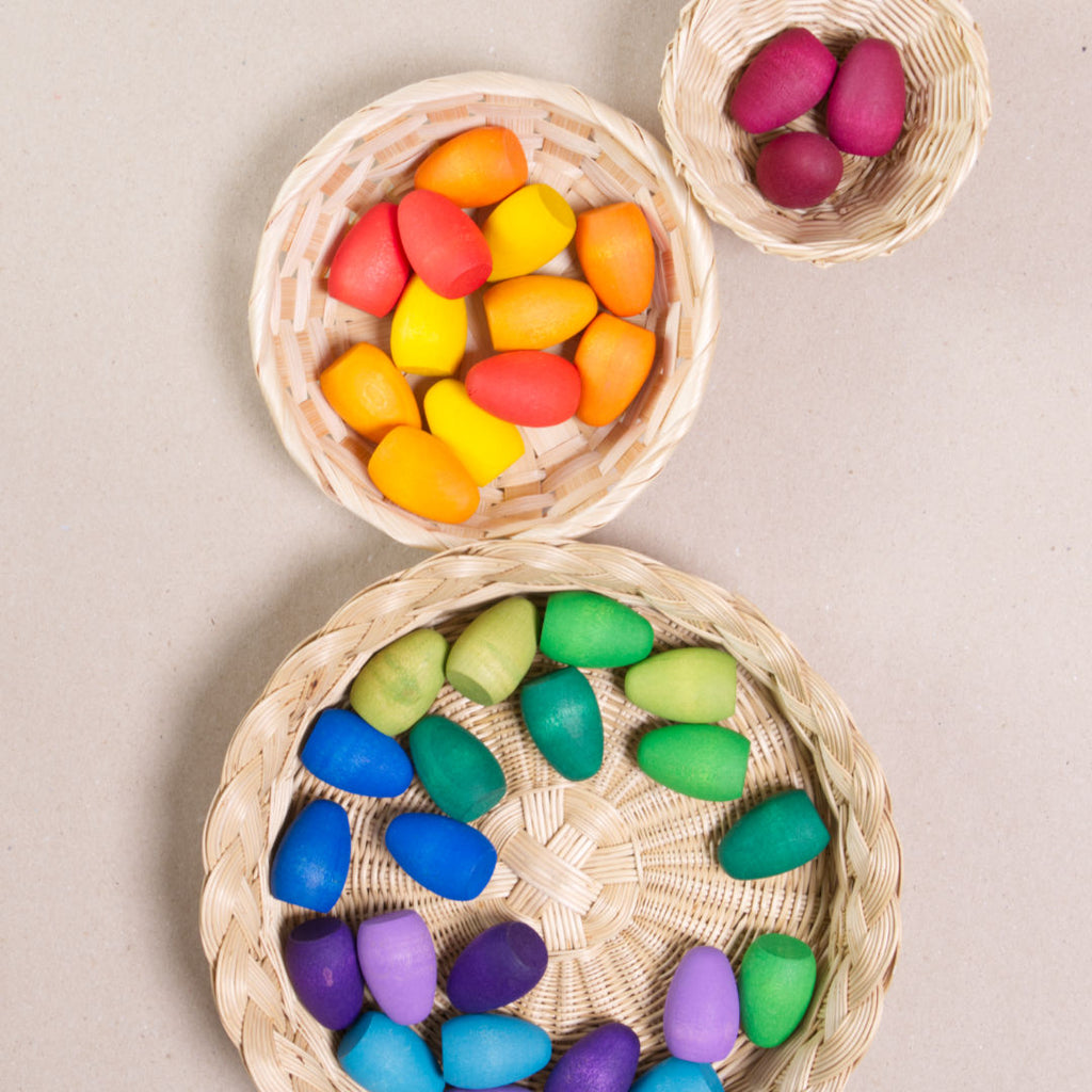 Komposition aus den Figuren aus dem Set Mandala Rainbow eggs von Grapat. Alle Holzfiguren sind bunt. Alle sind in vier Körbchen aufgeteilt.