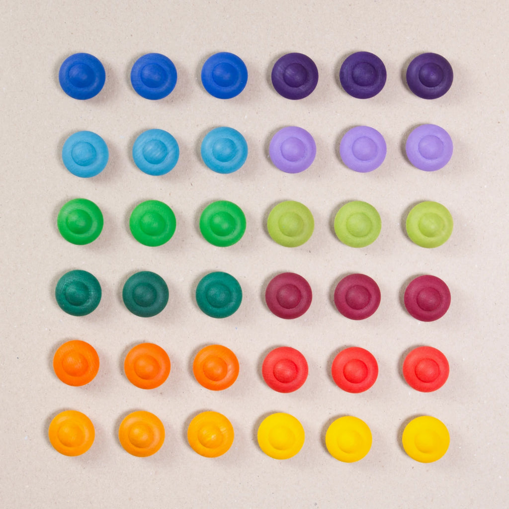 36 Regenbogen Blumen aus Holz von Grapat in 12 unterschiedlichen Farben. Dunkelblau, dunkellila, hellblau, pastelllila, grasgrün, hellgrün, dunkelgrün, dunkelrot, orange, rot, sonnengelb und senfgelb. Gemeinsam als Quadratischer Block aufgebaut. Ansicht von Oben.