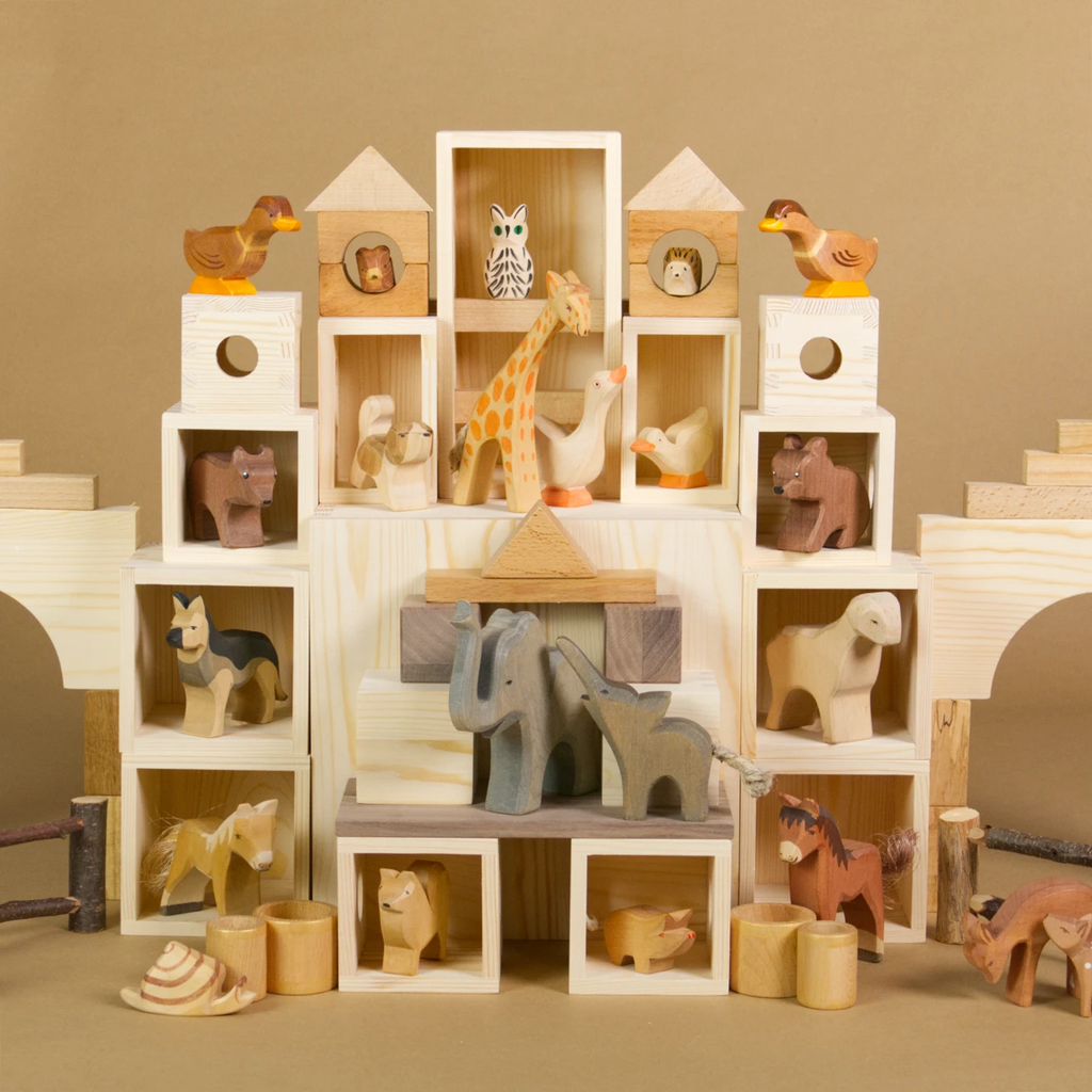 Eine MATZBOX-Idee: Die Bauteile der Matzbox sind symmetrisch angeordnet zu einem großen Spielhaus, in dem Holztiere von Ostheimer wohnen. Die Tiere haben alle ein Zimmer. Die Bauelemente, Holzkisten und Bausteine sind mit anderen Bauklötzen kombiniert.