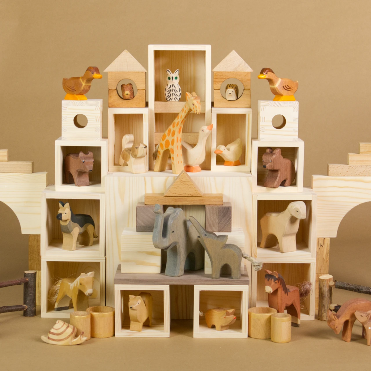 Eine MATZBOX-Idee: Die Bauteile der Matzbox sind symmetrisch angeordnet zu einem großen Spielhaus, in dem Holztiere von Ostheimer wohnen. Die Tiere haben alle ein Zimmer. Die Bauelemente, Holzkisten und Bausteine sind mit anderen Bauklötzen kombiniert.