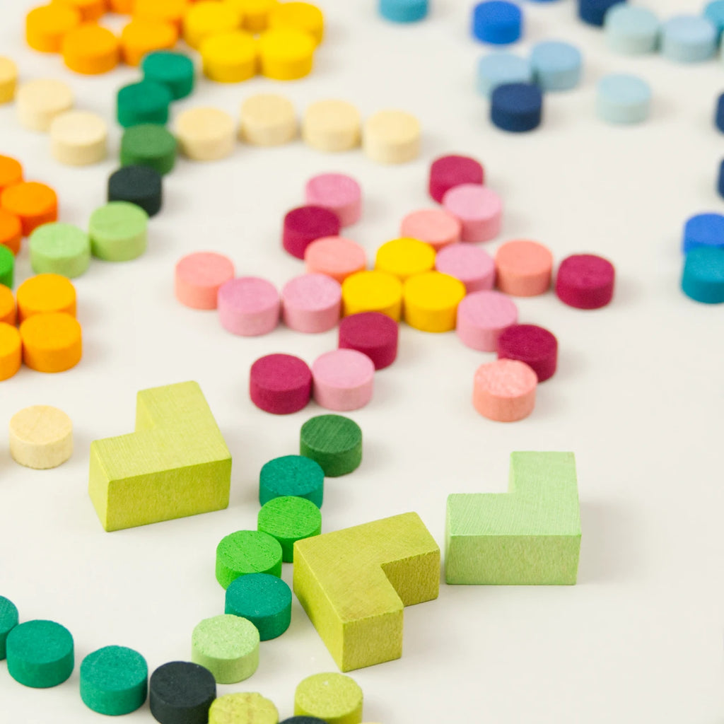 Grapat Mis Match and Bloom, Mosaik Elemente, 400 Teile, 36 Farbnuancen – bunte Zylinder- und Eckelemente locker auf weißem Hintergrund verteilt, im Vordergrund zwei grüne Eckelemente, drumherum leuchtende Farbtöne von Gelb, Rosa, Pink, Blau und Grün in runder und eckiger Form, Darstellung spielerischer Nutzung