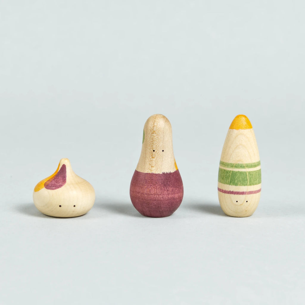 Drei organisch-geformte Holzfiguren mit Augen und weinrot, grün und orangenen Bemalungen.