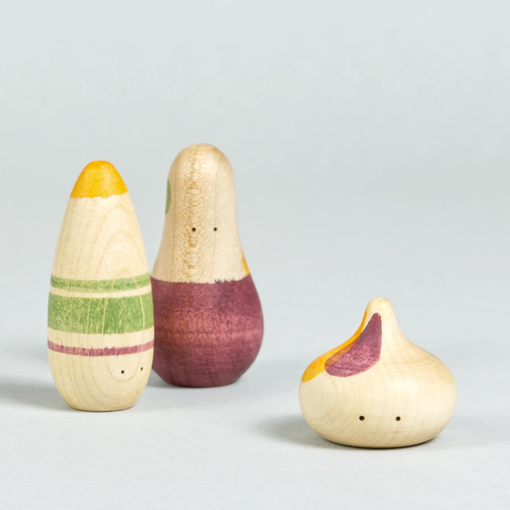 Drei organisch-geformte Holzfiguren mit Augen und weinrot, grün und orangenen Bemalungen.