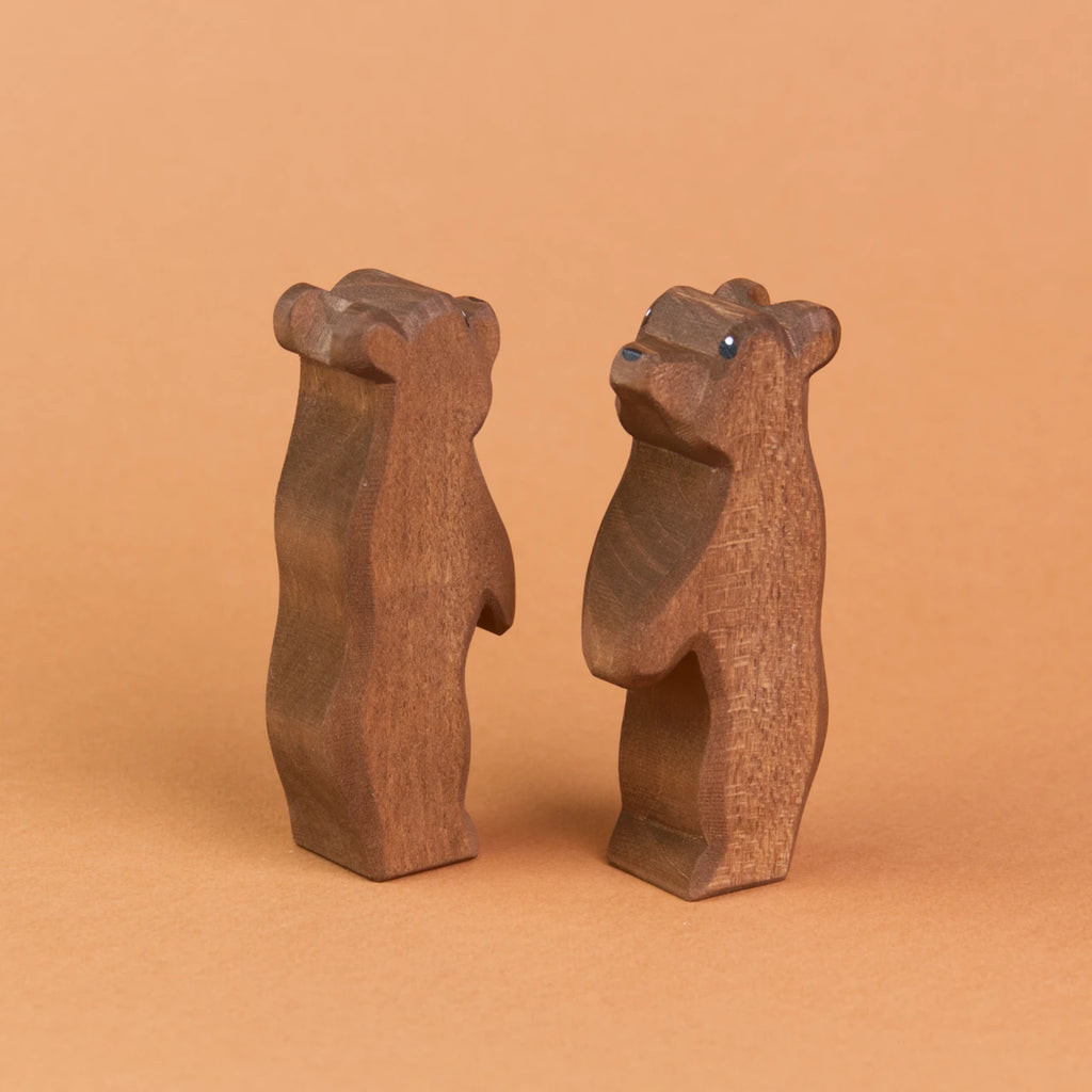 Zwei kleine Bären aus Holz sind schräg nebeneinander stehend zu sehen. Der recht Bär schaut nach vorne links hoch, der linke Bär schaut nach hinten rechts nach oben.