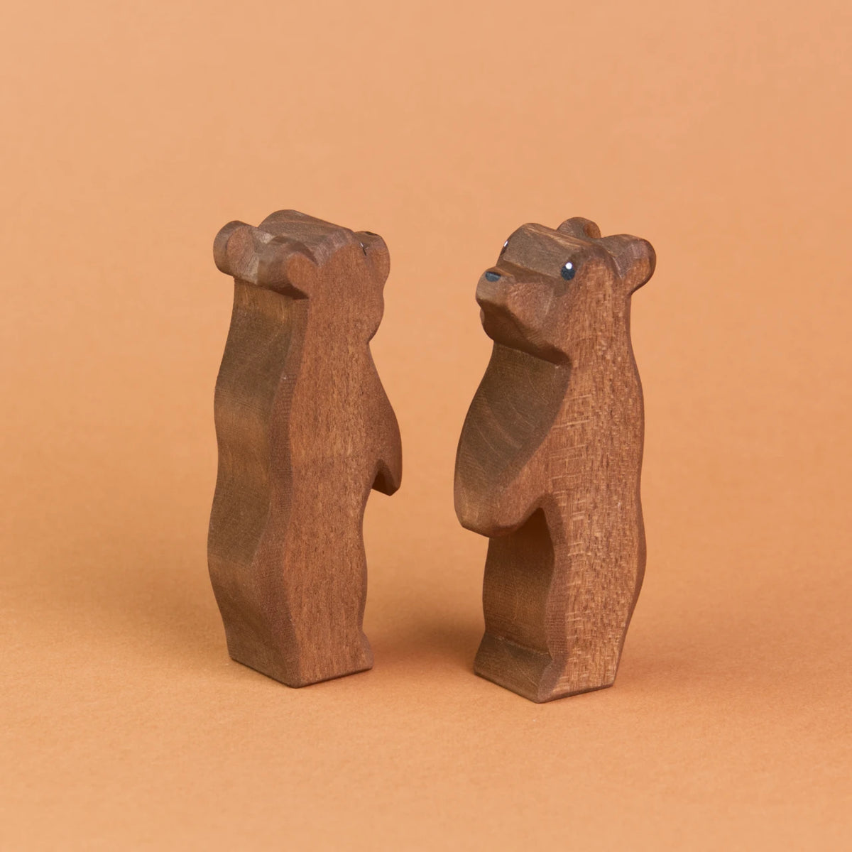 Zwei kleine Bären aus Holz sind schräg nebeneinander stehend zu sehen. Der recht Bär schaut nach vorne links hoch, der linke Bär schaut nach hinten rechts nach oben.