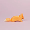 Es ist ein kleiner, schleichender Fuchs aus Holz von der Seite zu sehen, der nach rechts schaut. Sein Fell ist orangefarben und an seinem Maul und dem Ende seines Schwanzes ist es weiß. Er schaut nach unten und ist von der Marke Ostheimer.