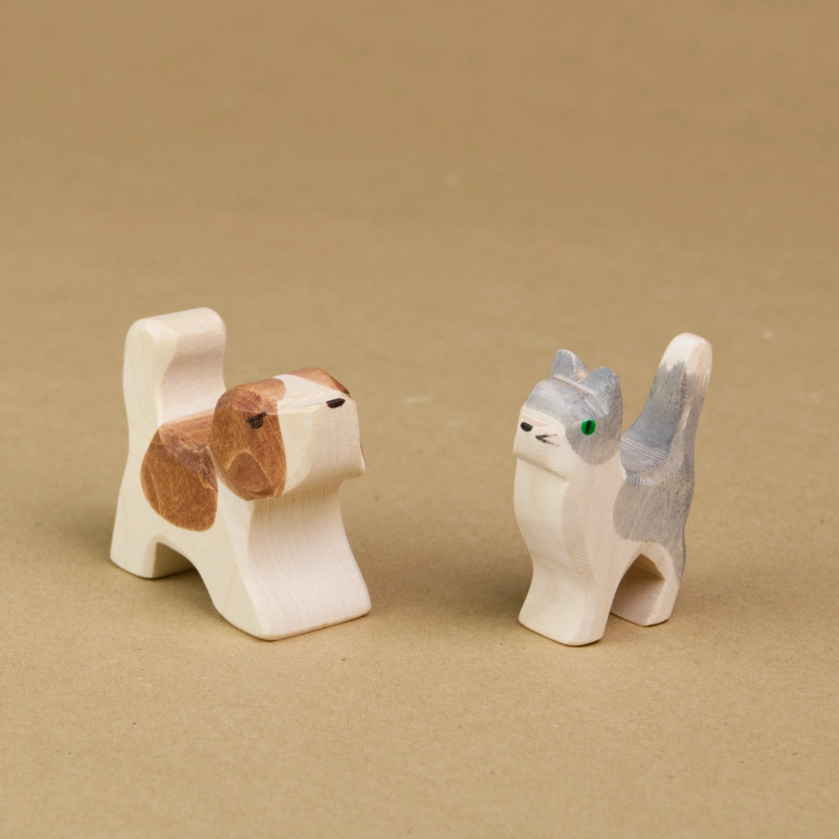 Eine kleine Katze mit weiß-grauem Fell und ein Bernhardiner Welpe mit weiß-braunem Fell stehen sich seitlich eingedreht gegenüber. Beide halten den Kopf, sowie den Schwanz hoch und sind von der Marke Ostheimer.