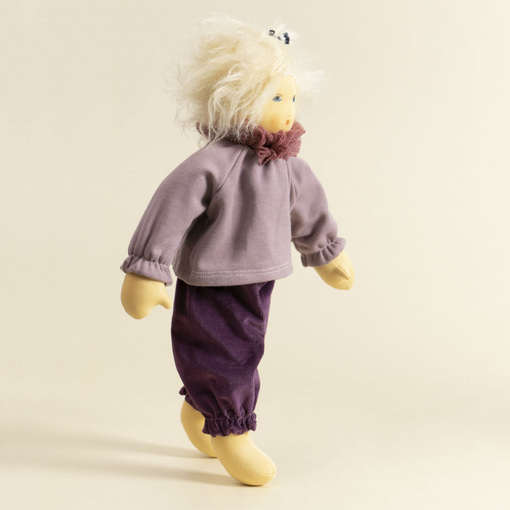 Nanchen Puppe mit heller Haut und hellblonde Haaren stehend. Sie trägt einen Pullover in Flieder mit Kragen und eine lila Hose.