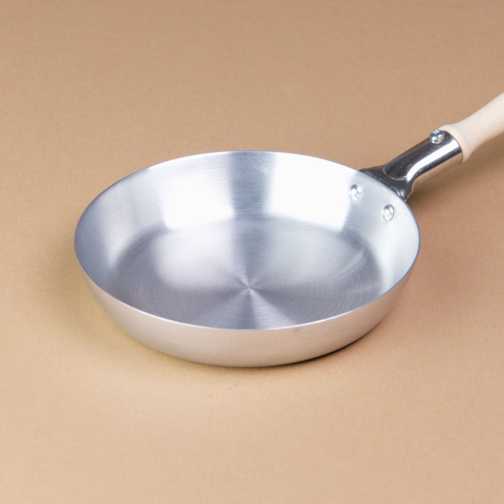 Eine Pfanne aus Aluminium mit Holzgriff hat einen Durchmesser von 10 cm.