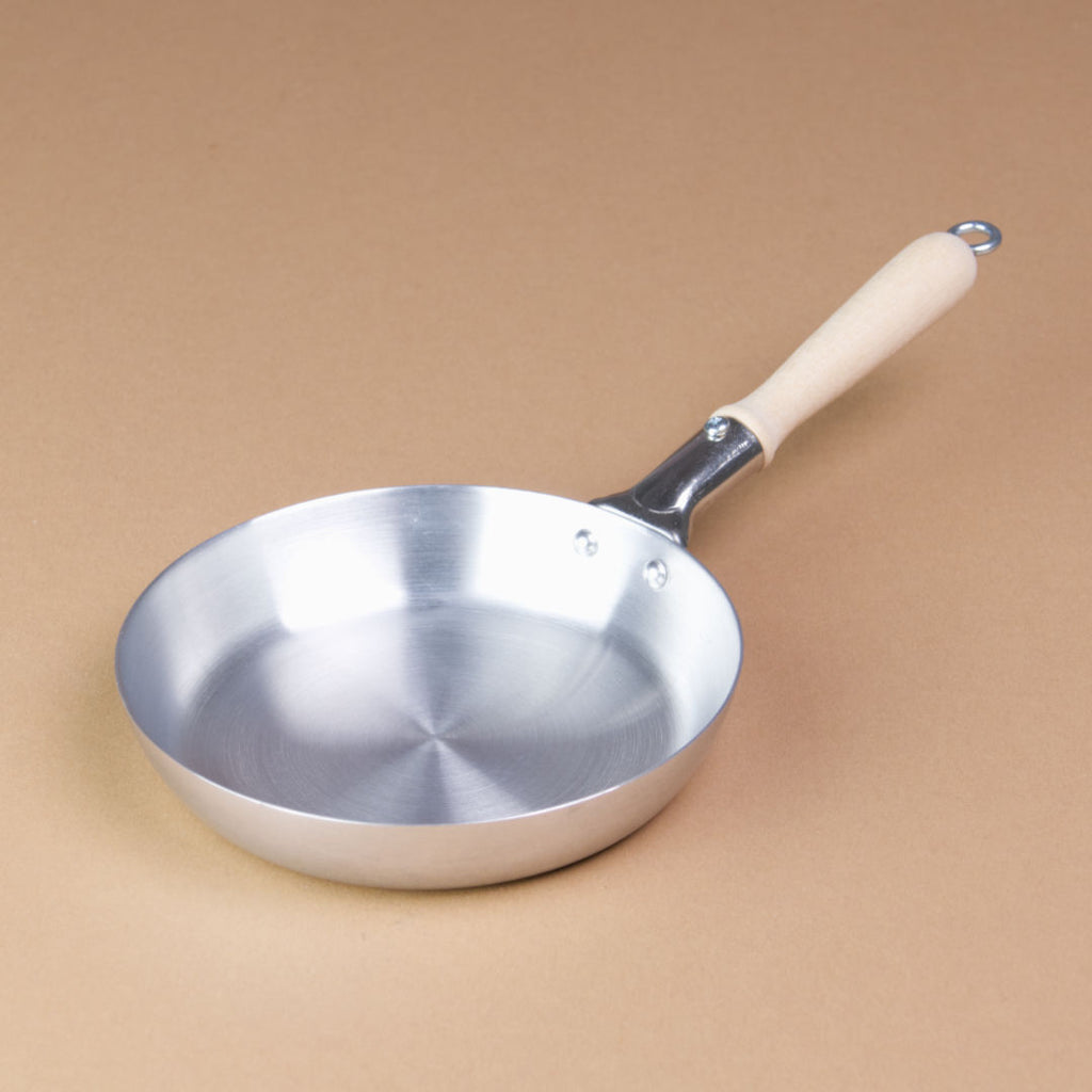 Eine Pfanne aus Aluminium mit Holzgriff hat einen Durchmesser von 10 cm.