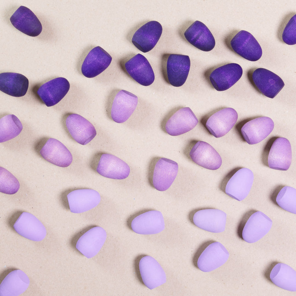 Komposition aus den Figuren aus dem Set Mandala purple eggs von Grapat. Alle Holzfiguren sind in drei unterschiedlichen Lilatönen.