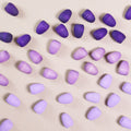 Komposition aus den Figuren aus dem Set Mandala purple eggs von Grapat. Alle Holzfiguren sind in drei unterschiedlichen Lilatönen.