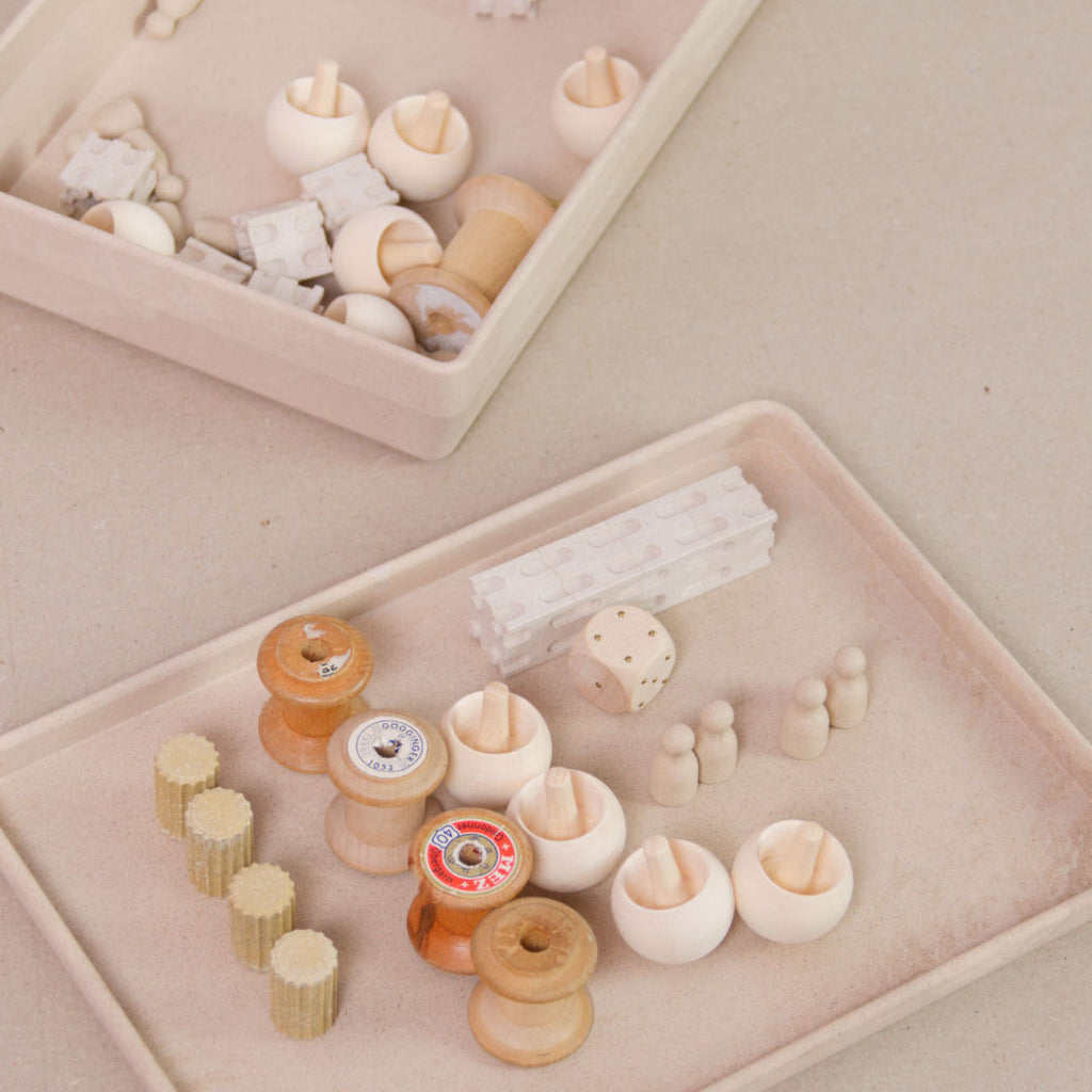 Komposition aus der aus recyclebarem Material bestehende naturfarbenen Box von Wissner mit kleinen Spielsteinen und Figuren.