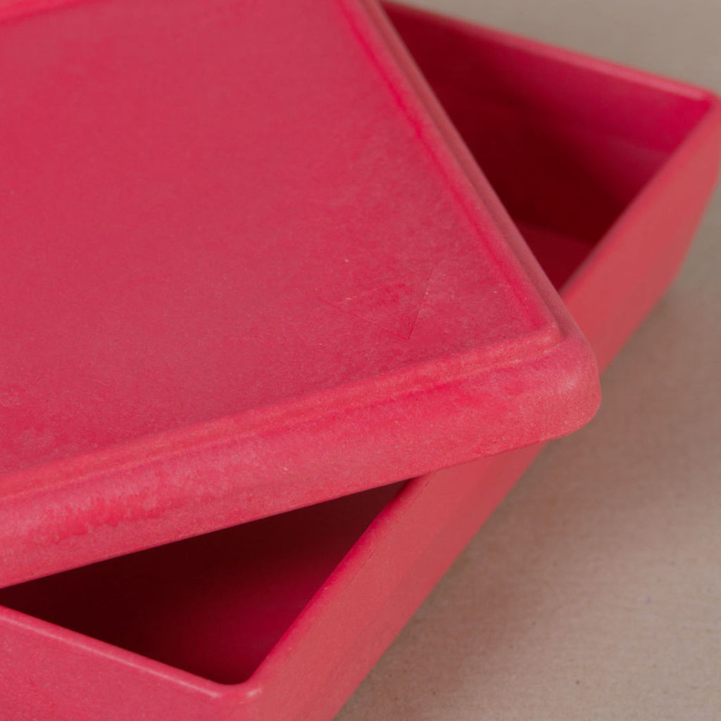 Nahaufnahme von der aus recyclebarem Material bestehende rote Box von Wissner, mit halboffenem Deckel daliegend.