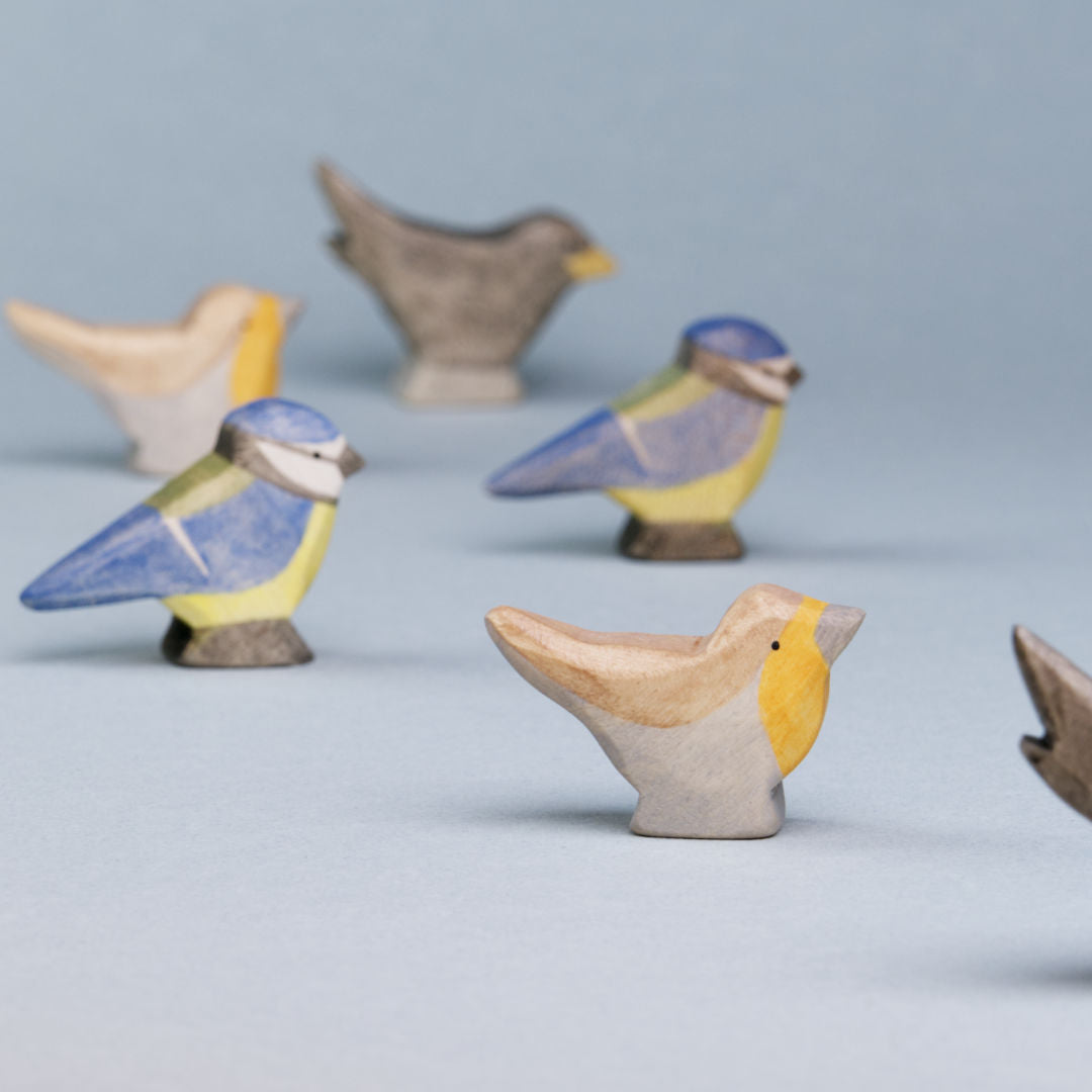 Komposition aus Holzvögeln der Firma Holzviecherl. Im Mittelpunkt Rotkehlchen, umspielt von Blaumeise und Amsel.