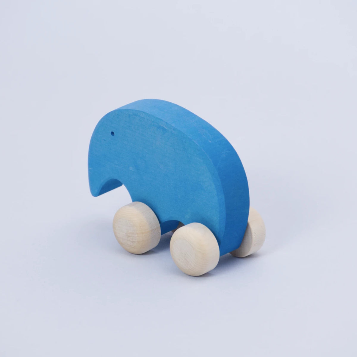 Ein blaues Schiebetier mit weißen Rollen von Goki Evolution ist schräg von hinten zu sehen. Die Form erinnert abstrahiert an einen Elefanten, dieser schaut nach hinten links. Sein Auge ist ein kleines gebohrtes Loch.