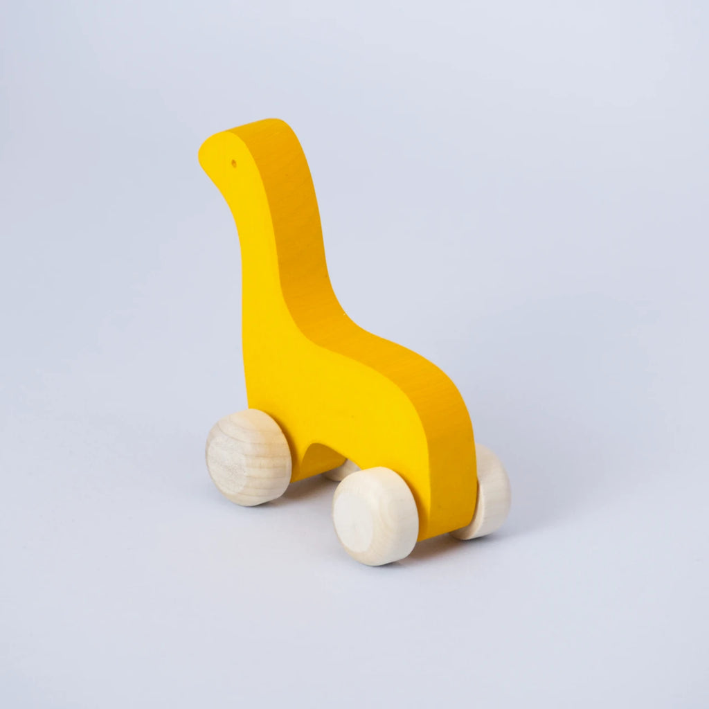 Ein gelbes Schiebetier mit weißen Rädern von Goki Evolution ist schräg von hinten zu sehen. Die Form erinnert an einen Dinosaurier mit langem Hals oder einer Giraffe. Das Tier schaut nach hinten links. Es ist aus Holz gefertigt und die Farbe ist ein intensives, freundliches Sonnenblumen Gelb.