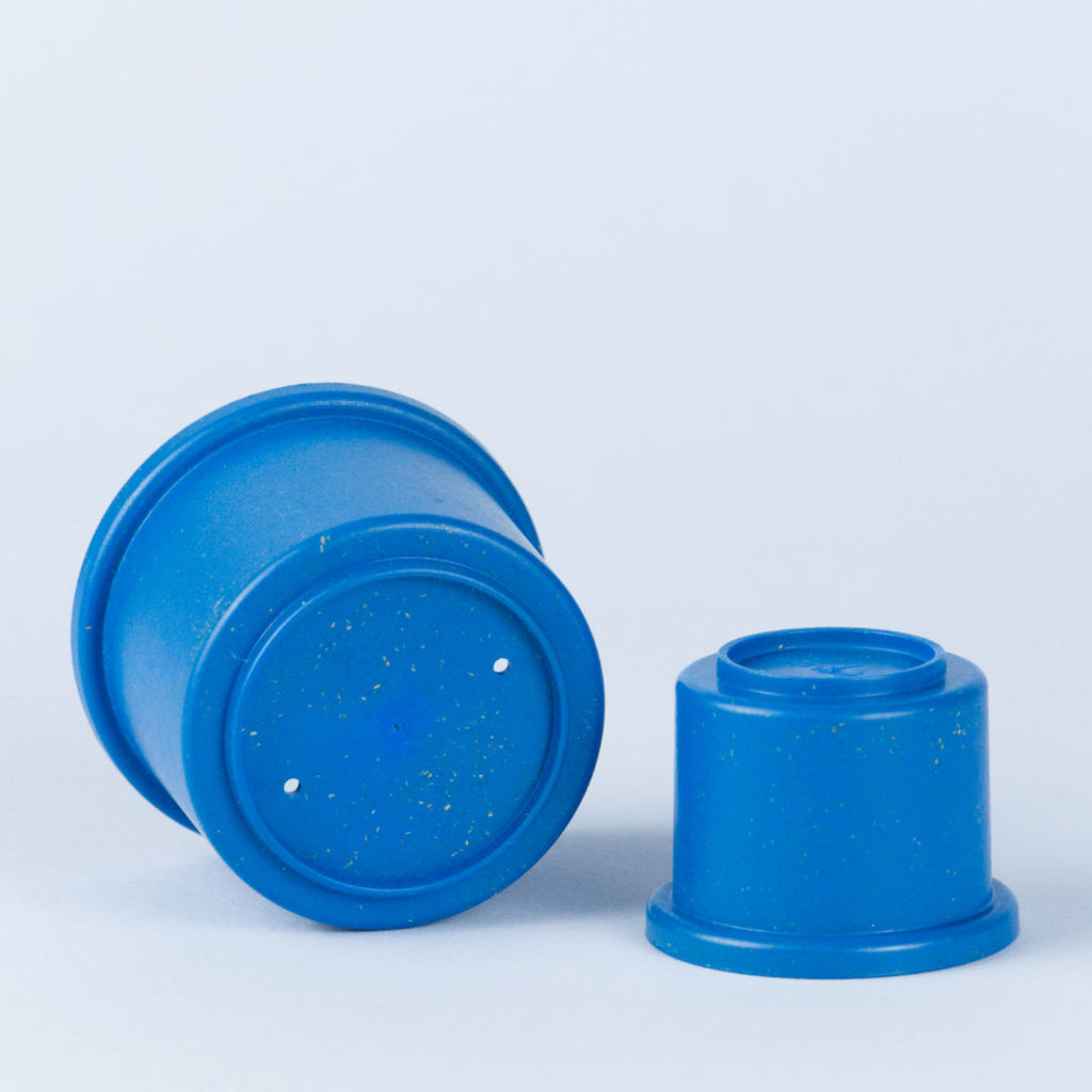 Zwei verschieden große, blaue Stapelbecher. Großer Stapelbecher mit zwei kleinen löchern.