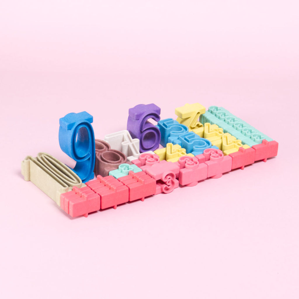 34 Stapelzahlen, liegend und stehend, sind gemeinsam als Block angeordnet. Die Stapelzahlen decken den Zahlenraum zwischen 1 und 10 ab und haben die Farben rot, beige, braun, lila, grün, gelb, blau und rosa.