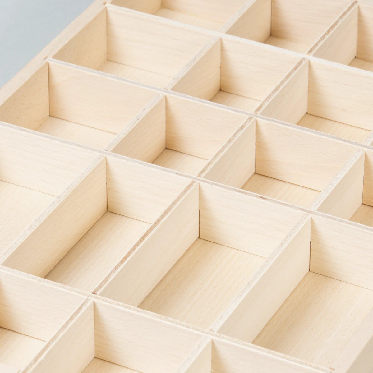 Die Detailsansicht der Sortierbox Tinker Tray aus Naturholz mit vielen verschieden großen Fächern zum Sammeln, Ordnen und Aufbewahren von Spielzeug, hier noch ungefülllt zu sehen.