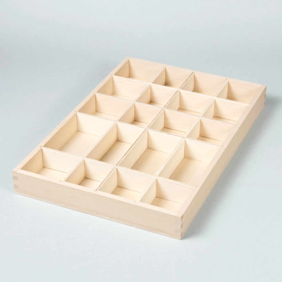 Das Tinker Tray aus Naturholz mit vielen verschieden großen Fächern zum Sammeln, Sortieren und Aufbewahren von Spielzeug, hier noch ungefülllt zu sehen.