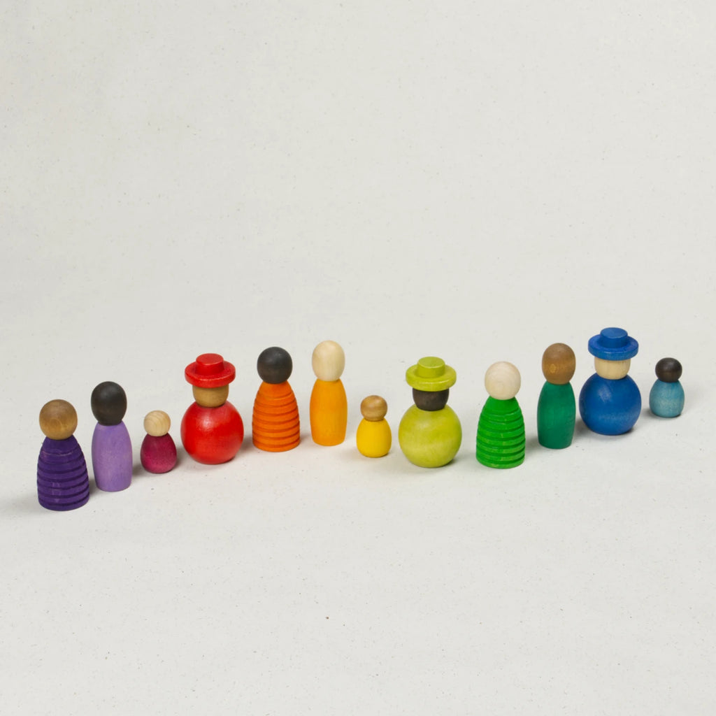 Sammlung verschiedener bunter Holzfiguren mit unterschiedlichen Hautfarben, Formen und Größen, in eine Reihe gestellt.