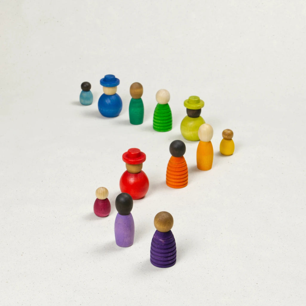 Sammlung verschiedener bunter Holzfiguren mit unterschiedlichen Hautfarben, Formen und Größen im Zickzack angeordnet.