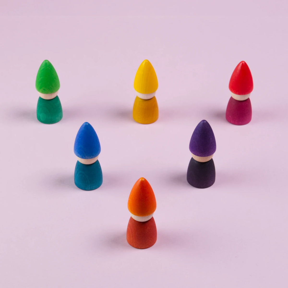 Sechs Figuren in grün, gelb, rot, blau, lila und orange, sind in einem Dreieck mit nach unten zeigender Spitze angeordnet. Alle haben kein Gesicht und sind von Grapat gefertigt.