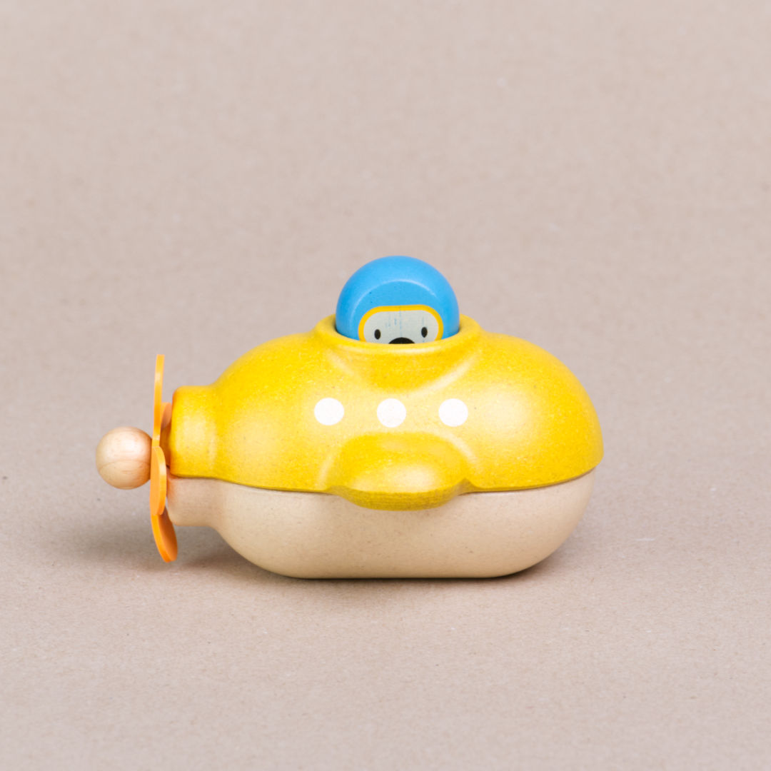 Seitenansicht des gelben U-Boots von Plan Toys mit herausnehmbaren Insassen in blauem Taucheranzug und gelber Taucherbrille. Der Taucher schaut einen an.