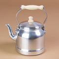 Ein Wasserkessel aus Aluminium mit bewegbarem Holzgriff und abnehmbarem Deckel.