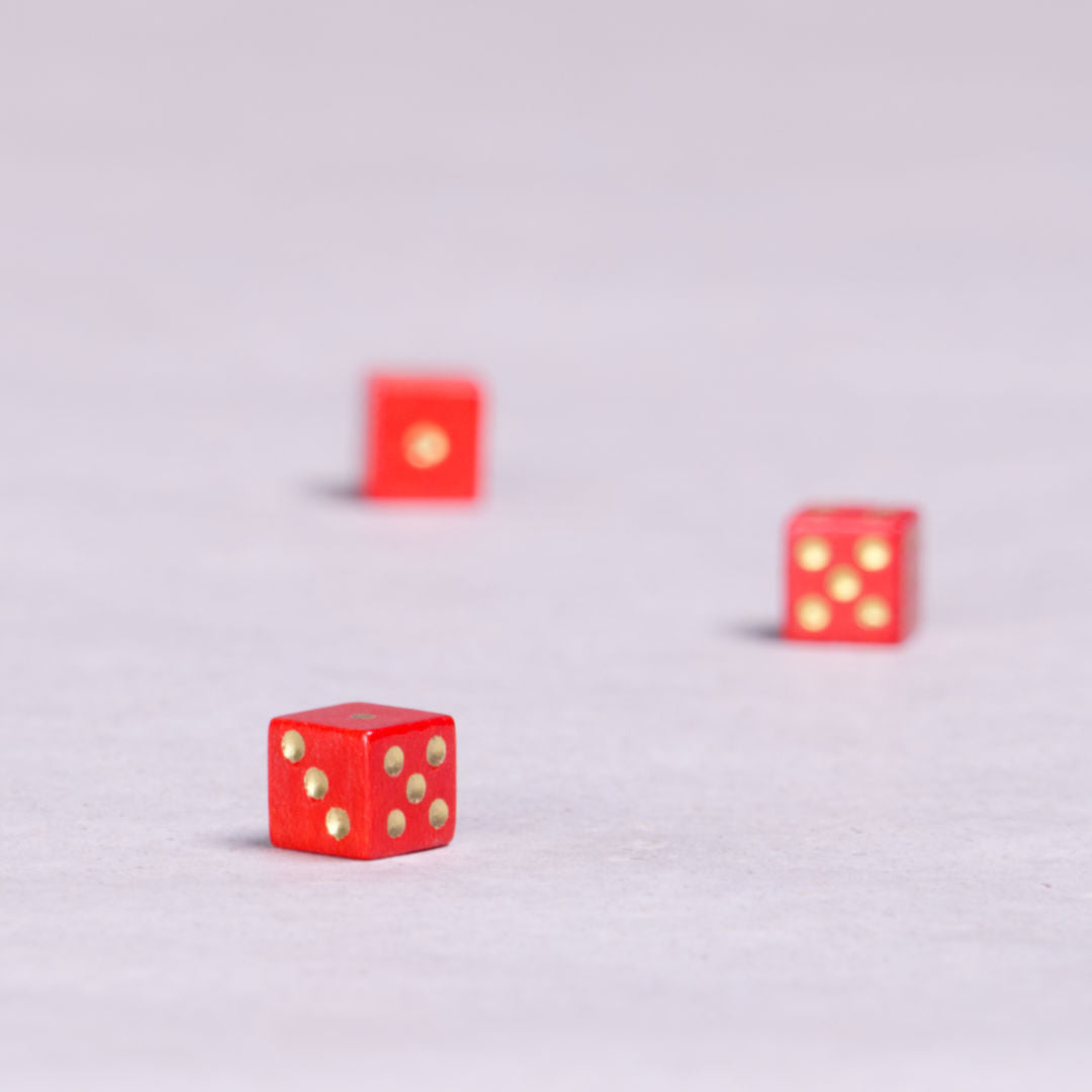 Drei rote kleine Spielwürfel mit goldenen Punkten.