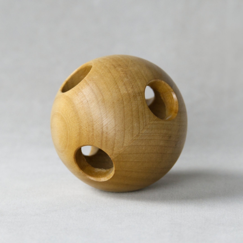 Greifling aus Holz in Ballform mit kreisrunden Öffnungen