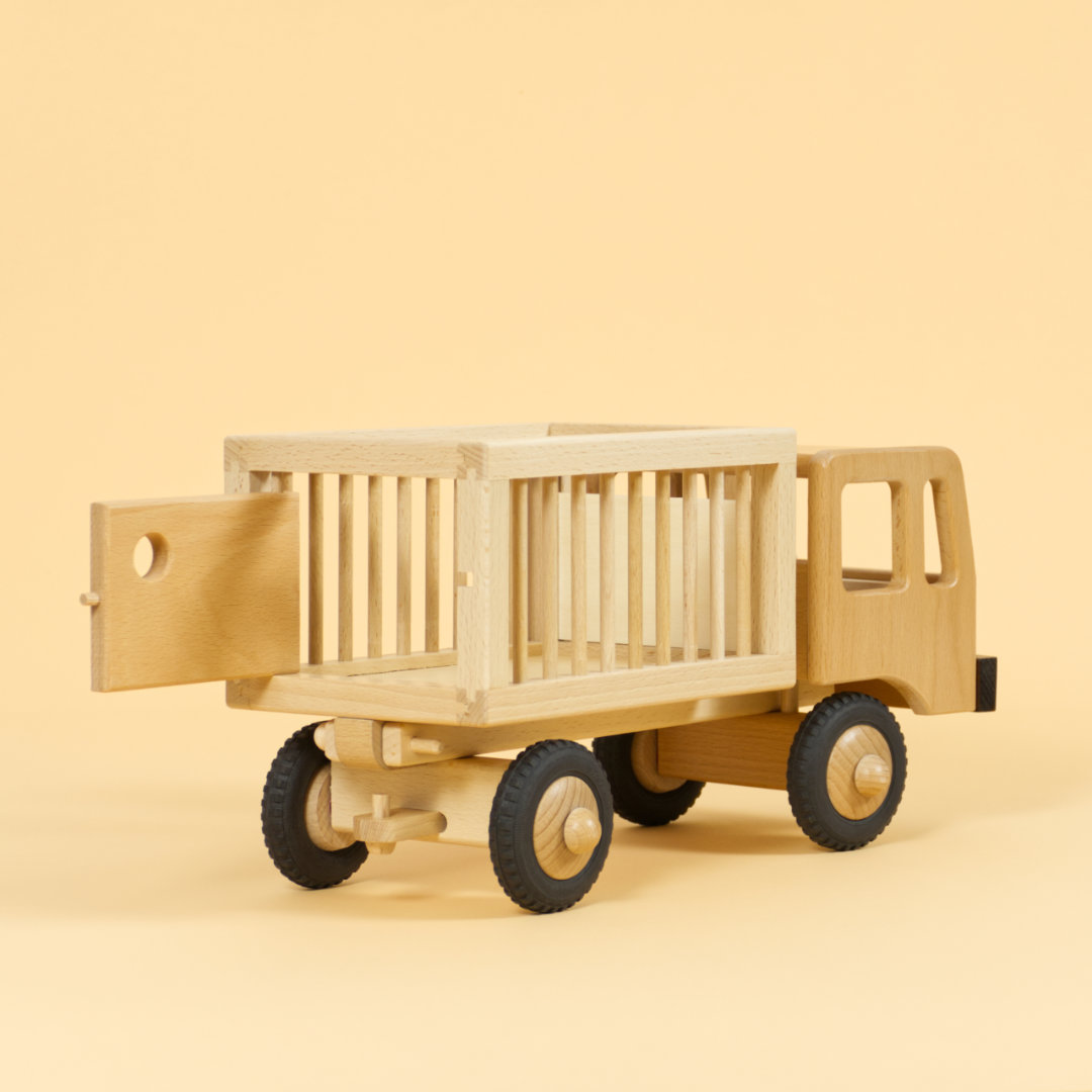 Holzfahrzeug Zirkuswagen für Tiere aus naturlackiertem Buchenholz und Reifen aus Vollgummi, Anhänger mit Gitterstäben an der Seite und geöffneter Tür hinten