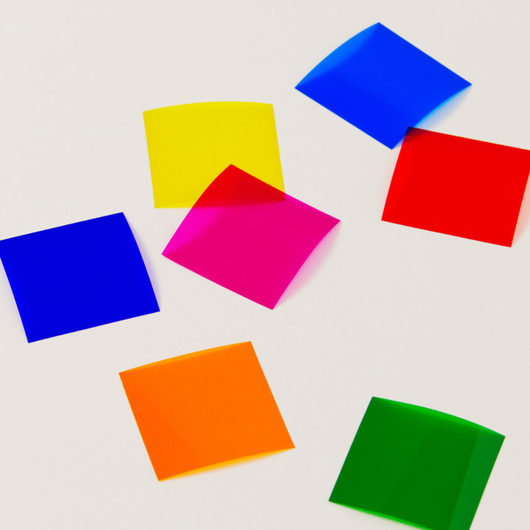 Sieben Farbplättchen auf transparenter Folie in Regenbogen-Farben ausgebreitet