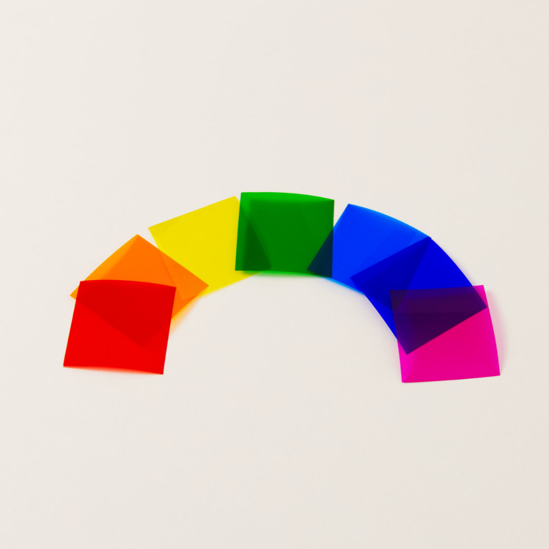 Sieben Farbplättchen auf transparenter Folie in Regenbogen-Farben ausgebreitet