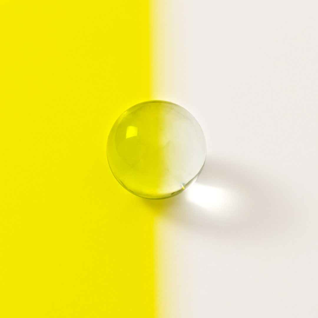 Farbplättchen aus transparenter Folie in Gelb vor Murmel