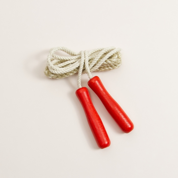 Springseil mit roten Griffen aus Buchenholz und weißes Seil aus Baumwolle aufgerollt