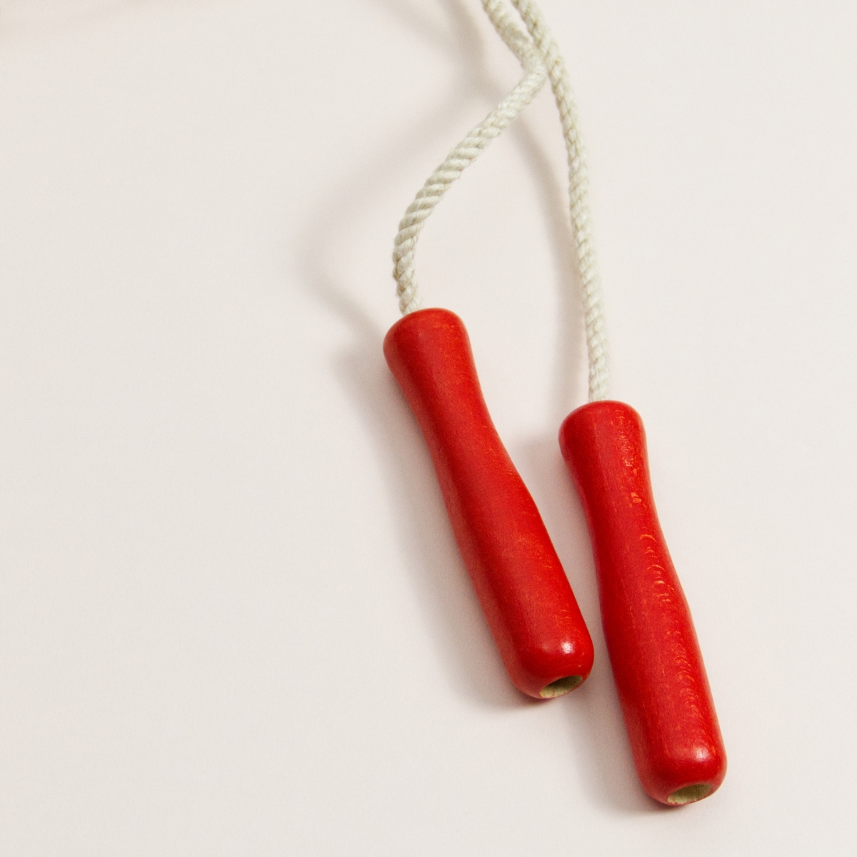 Springseil mit roten Griffen aus Buchenholz und weißes Seil aus Baumwolle Detailaufnahme der Griffe