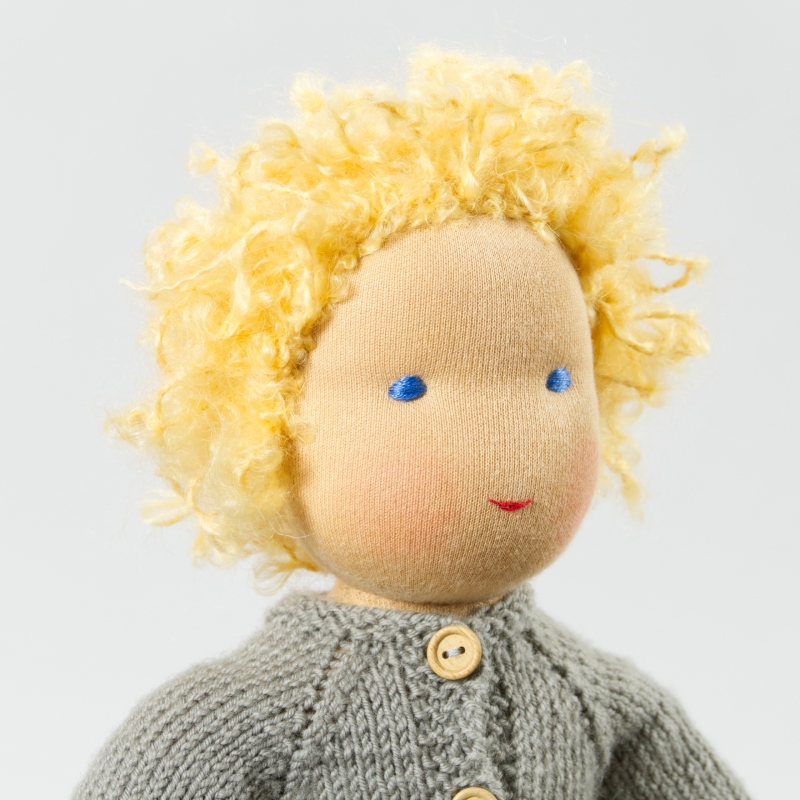 Puppe mit hellem Hautton nach Waldorf-Art, kurze blonde Haare, gekleidet in grauen Strickanzug