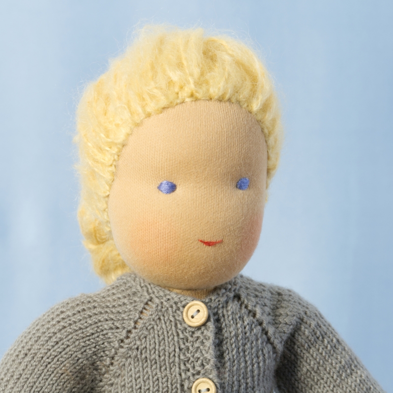 Puppe mit hellem Hautton nach Waldorf-Art, geflochtene lange blonde Haare, gekleidet in grauen Strickanzug