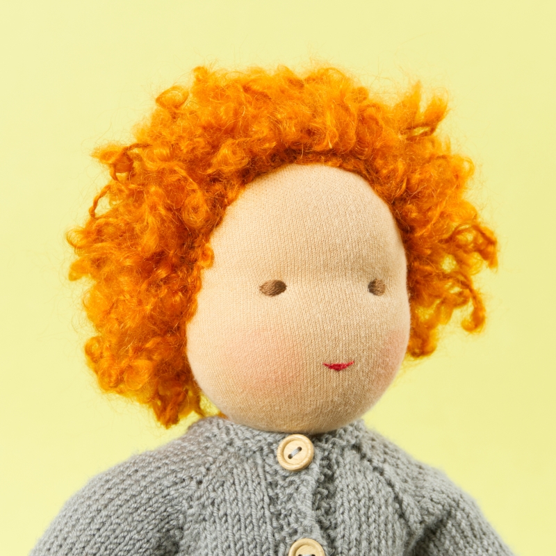 Puppe mit hellem Hautton nach Waldorf-Art, kurze rote Haare, gekleidet in grauen Strickanzug