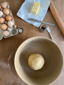 Teig für Kuchen in Schüssel, Eier und Butter stehen daneben