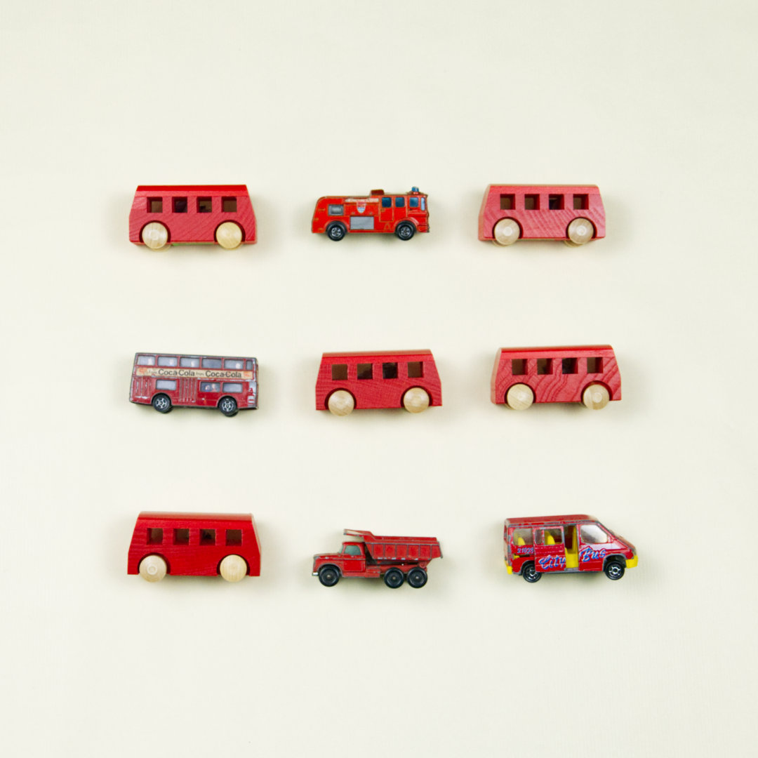 Anordnung von kleinen roten Fahrzeugen (Spielbusse und Feuerwehr)