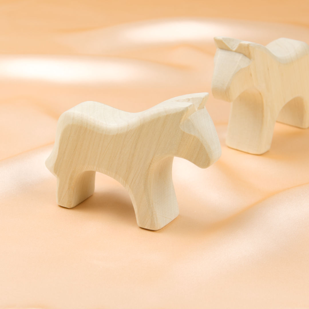 Zwei schlichte Holz-Pferde in hellem Holz aus verschiedenen Perspektiven